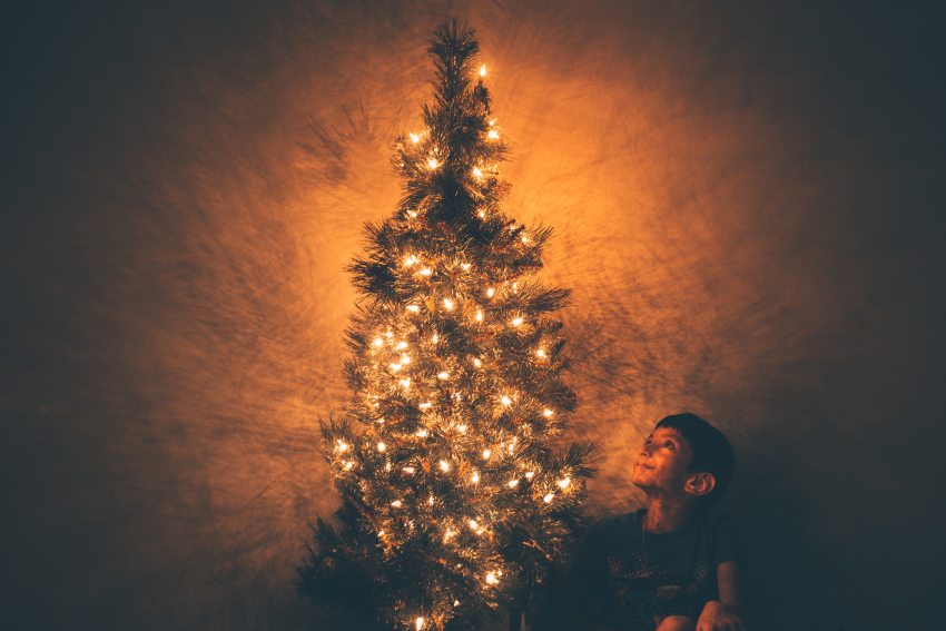 fiú karácsonyfa mellett