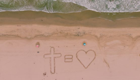Egy kereszt és egy szív a homokba rajzolva