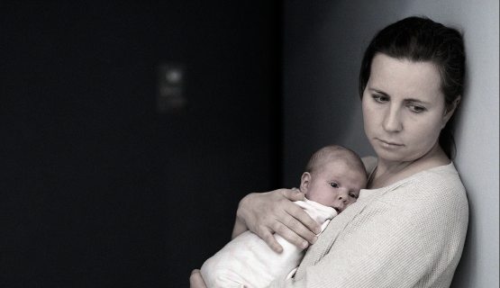 szomorú arcú nő kisbabával
