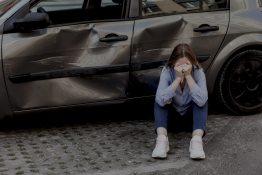 Szomorú nő egy összetört autó előtt