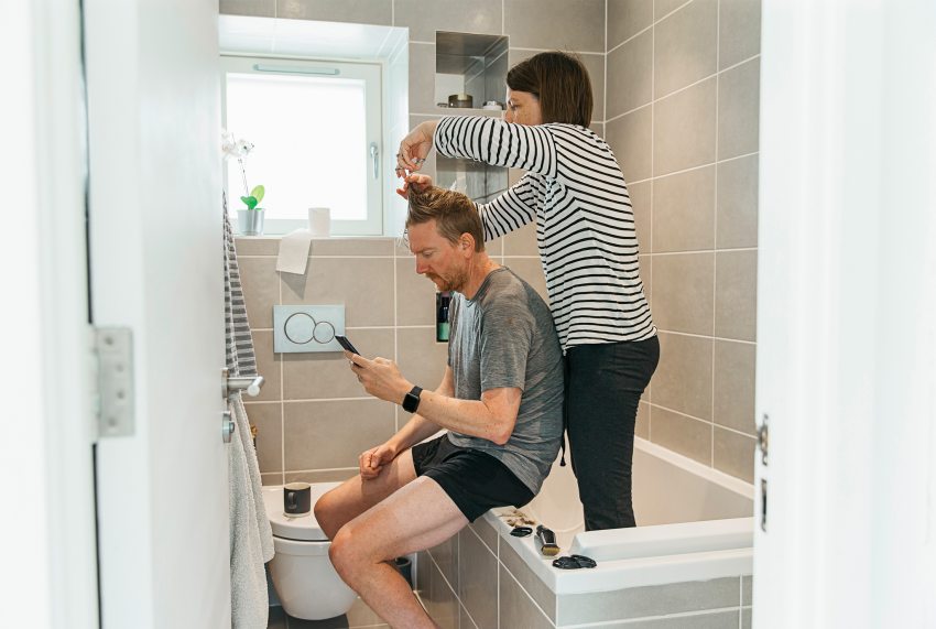 Egy nő a párja haját vágja a fürdőszobába, a koronavírus miatti karantén idején