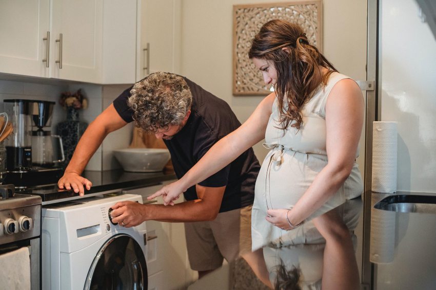 Egy pár együtt próbálja megszerelni a mosógépet, munkamegosztás