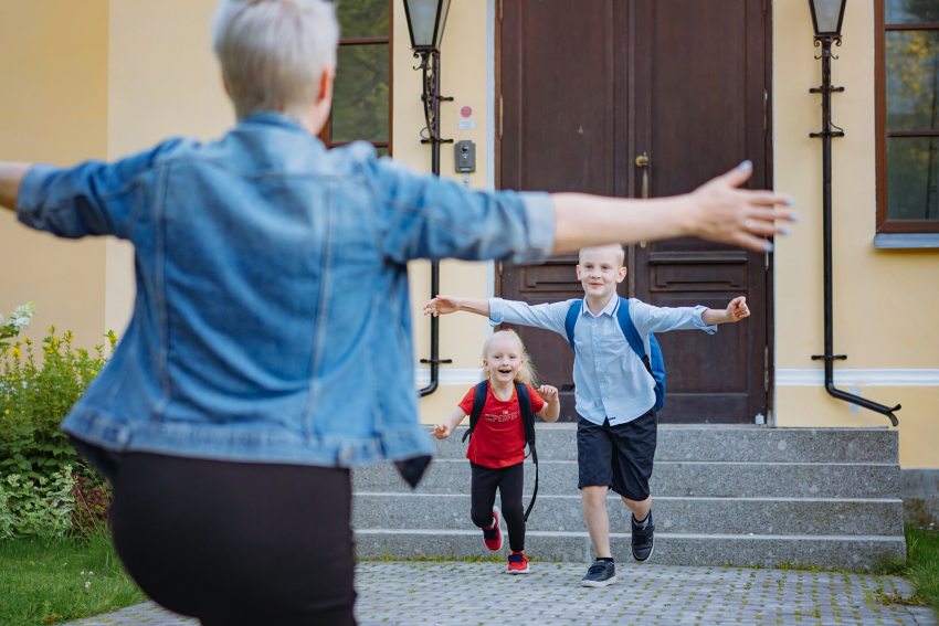 kisfiú és kislány szalad egy széttárt kezű nő felé