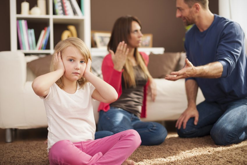 szülők beszélnek miközben kisgyerek befogja fülét
