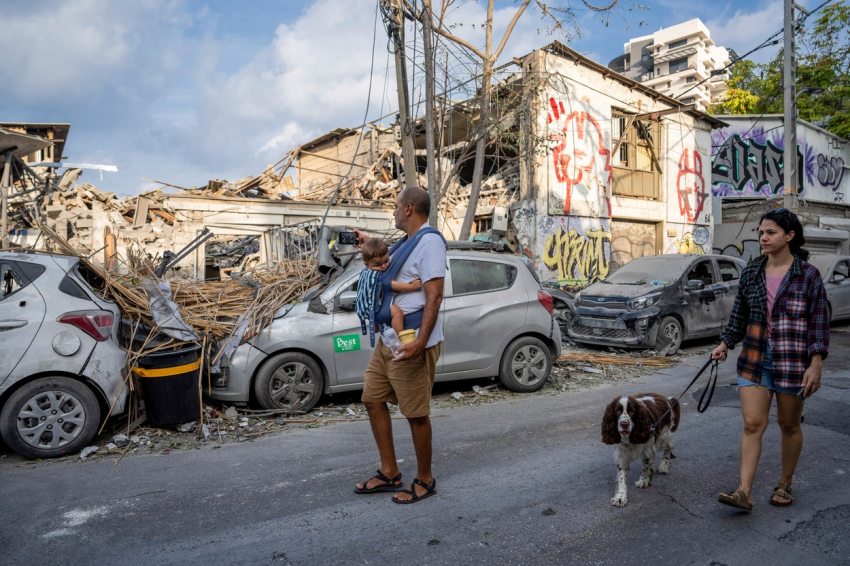 Férfi kisbabával sétál Tel-Avivban a Hamász bombatámadása után