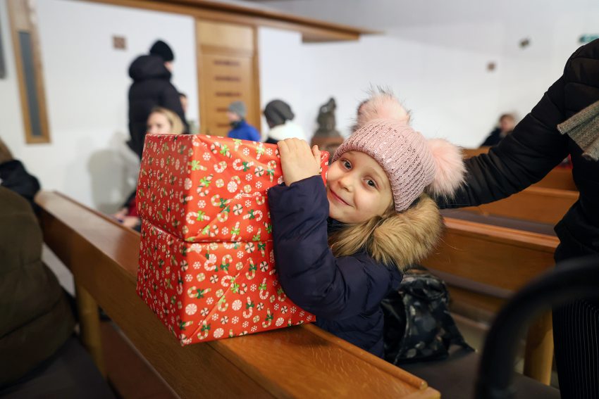 menekült kislány a Katolikus Karitász ajándékdobozával