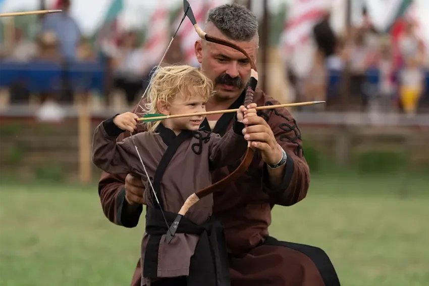 Gábor Kopecsni teaching archery to a young boy