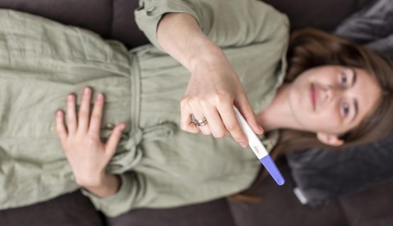 Egy nő terhességi teszttel a kezében