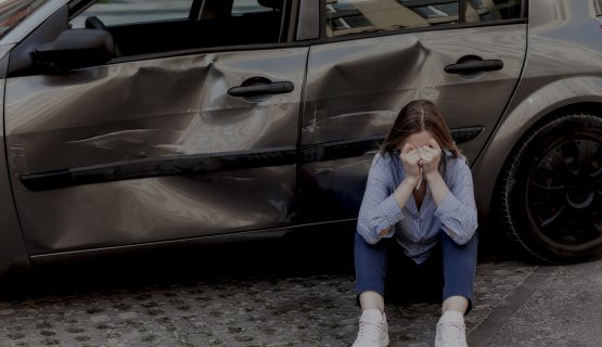 Szomorú nő egy összetört autó előtt