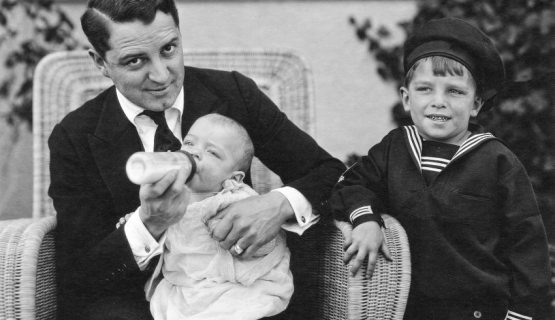 father feeding a baby from a bottle in the 1920s