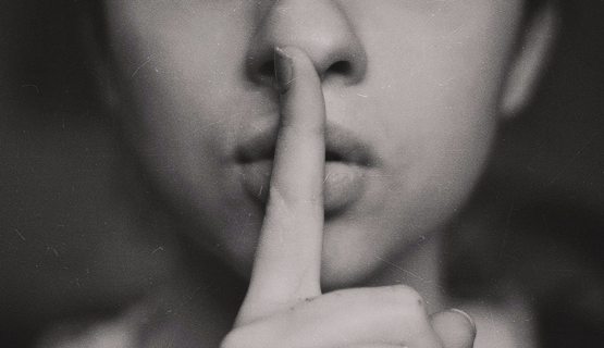 Családi titkot őrző nő, az ujját a szájához teszi