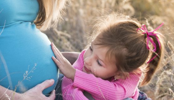 kislány fogja egy várandós nő pocakját