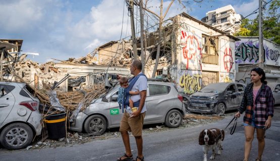 Férfi kisbabával sétál Tel-Avivban a Hamász bombatámadása után
