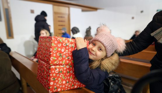 menekült kislány a Katolikus Karitász ajándékdobozával