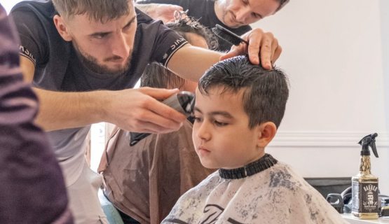 Volunteer hairdresser giving a haircut to a Ukranian refugee boy