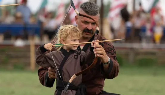 Gábor Kopecsni teaching archery to a young boy