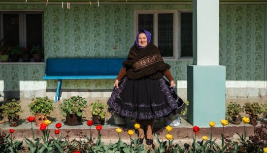 A Swabian woman in front of her house in Vojvodina in traditional Swabian attire
