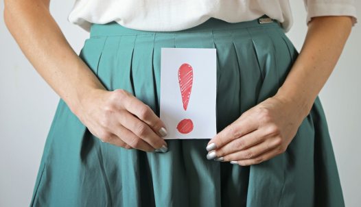 inkontinencia problémára utaló felkiáltójeles tábla nő kezében