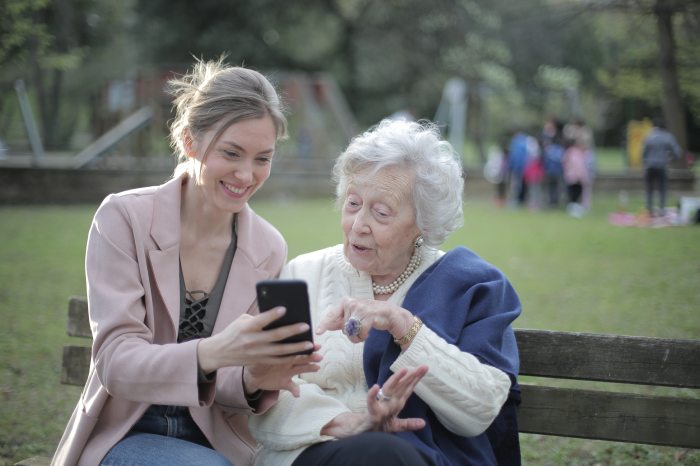 Fiatal nő és idős néni mobiltelefonnal