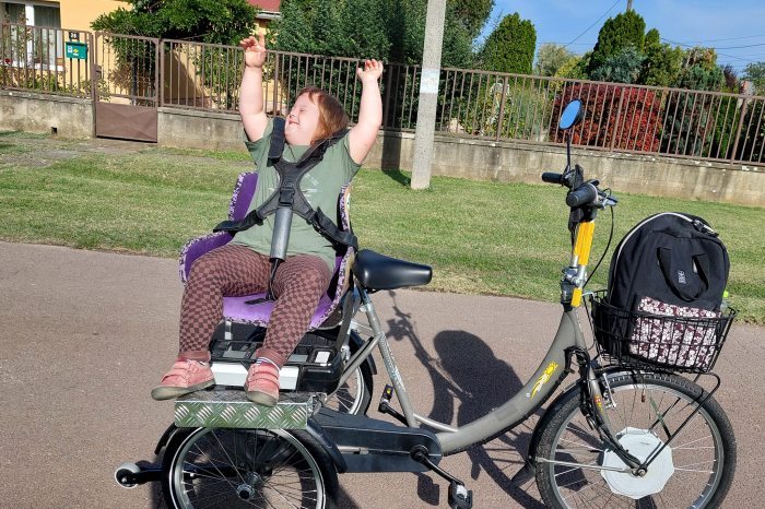 A girl with disabilities sitting on the back of a specially converted bike