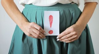 inkontinencia problémára utaló felkiáltójeles tábla nő kezében