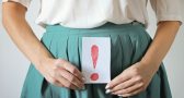 inkontinencia problémára utaló felkiáltójeles tábla nő kezében