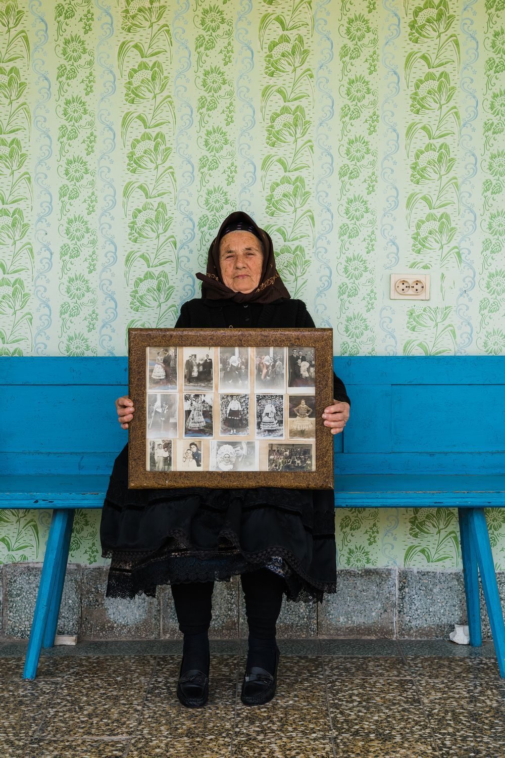 Swabian lady in traditional attire holding a framed picture with several family photographs