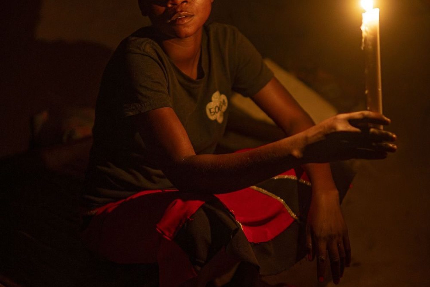 a girl with a candle stick in a hut in the Congo