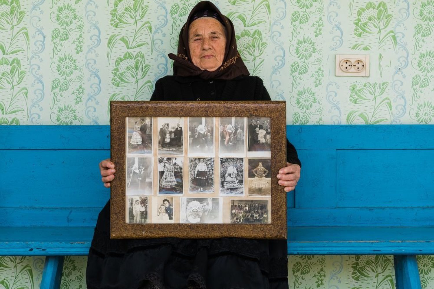 Swabian lady in traditional attire holding a framed picture with several family photographs