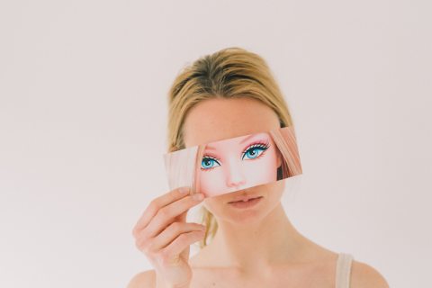 Egy nő arca, előtte egy barbie baba képével