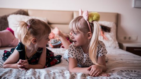 Kislányok, barátnők beszélgetnek az ágyon