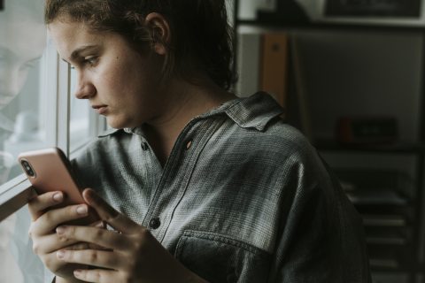 Kiközösített iskolás gyerek telefonnal a kezében