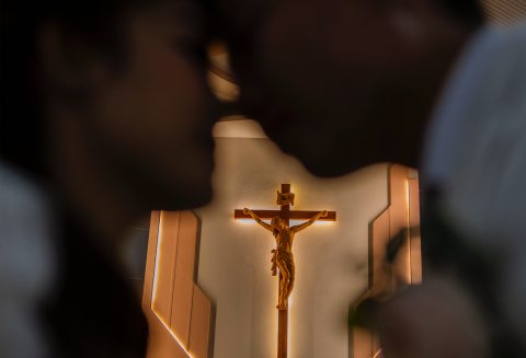Kereszt előtt egymásra néző pár