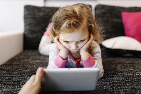 mérgesen néző kislány tablet előtt