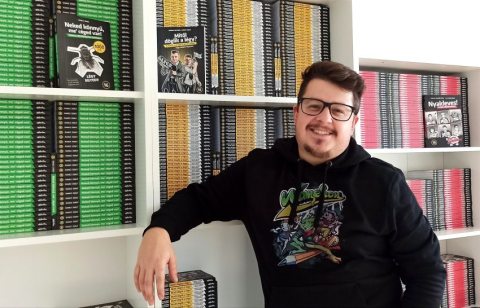 Zsolt Rancz in front of a bookcase with his books on
