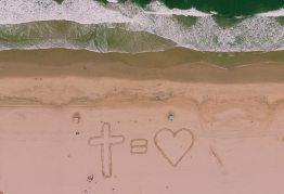 Egy kereszt és egy szív a homokba rajzolva